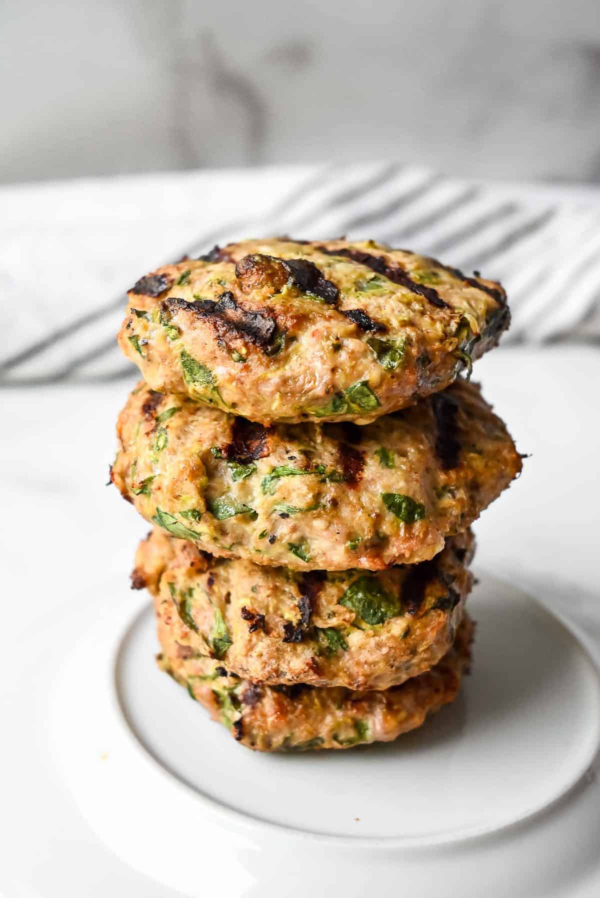 turkey burgers stacked on a white plate.