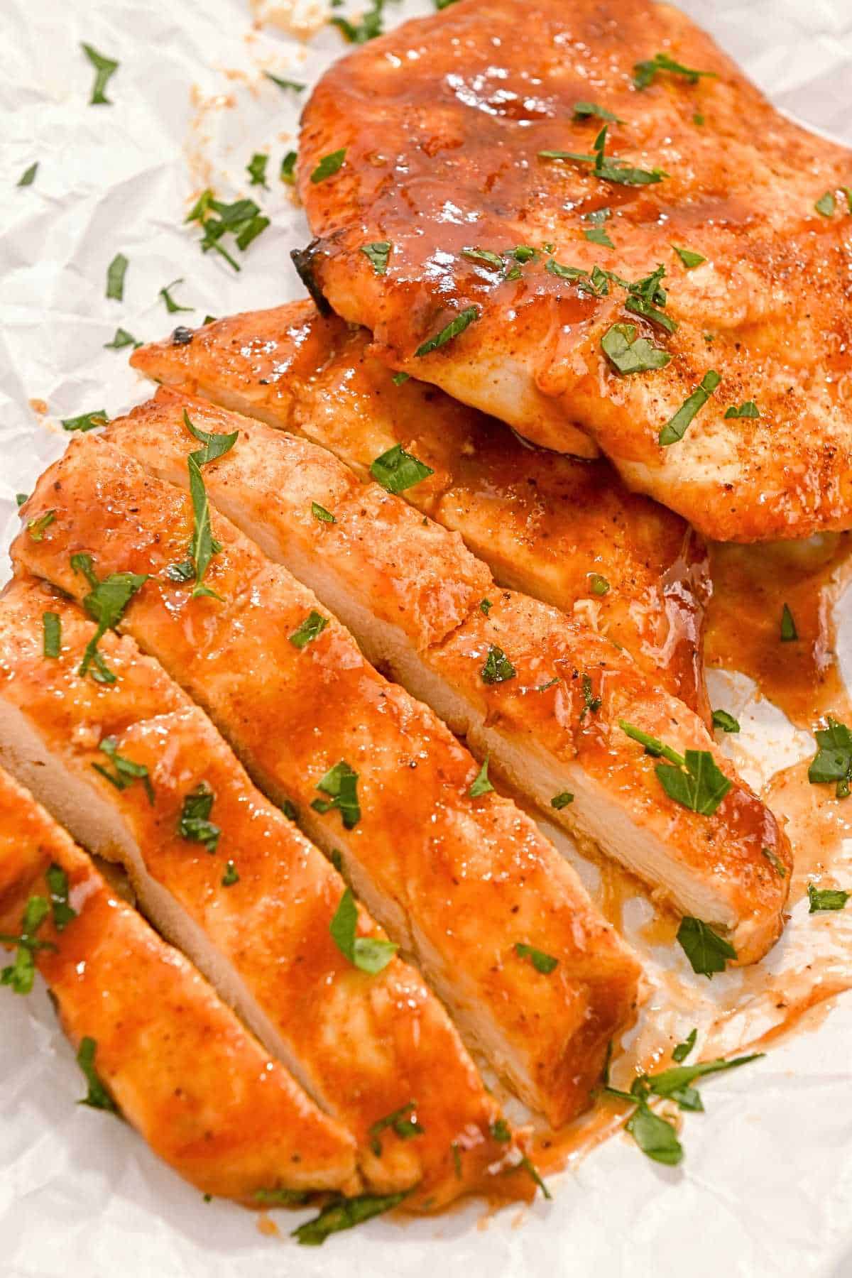 sliced air fryer bbq chicken breast topped with parsley.