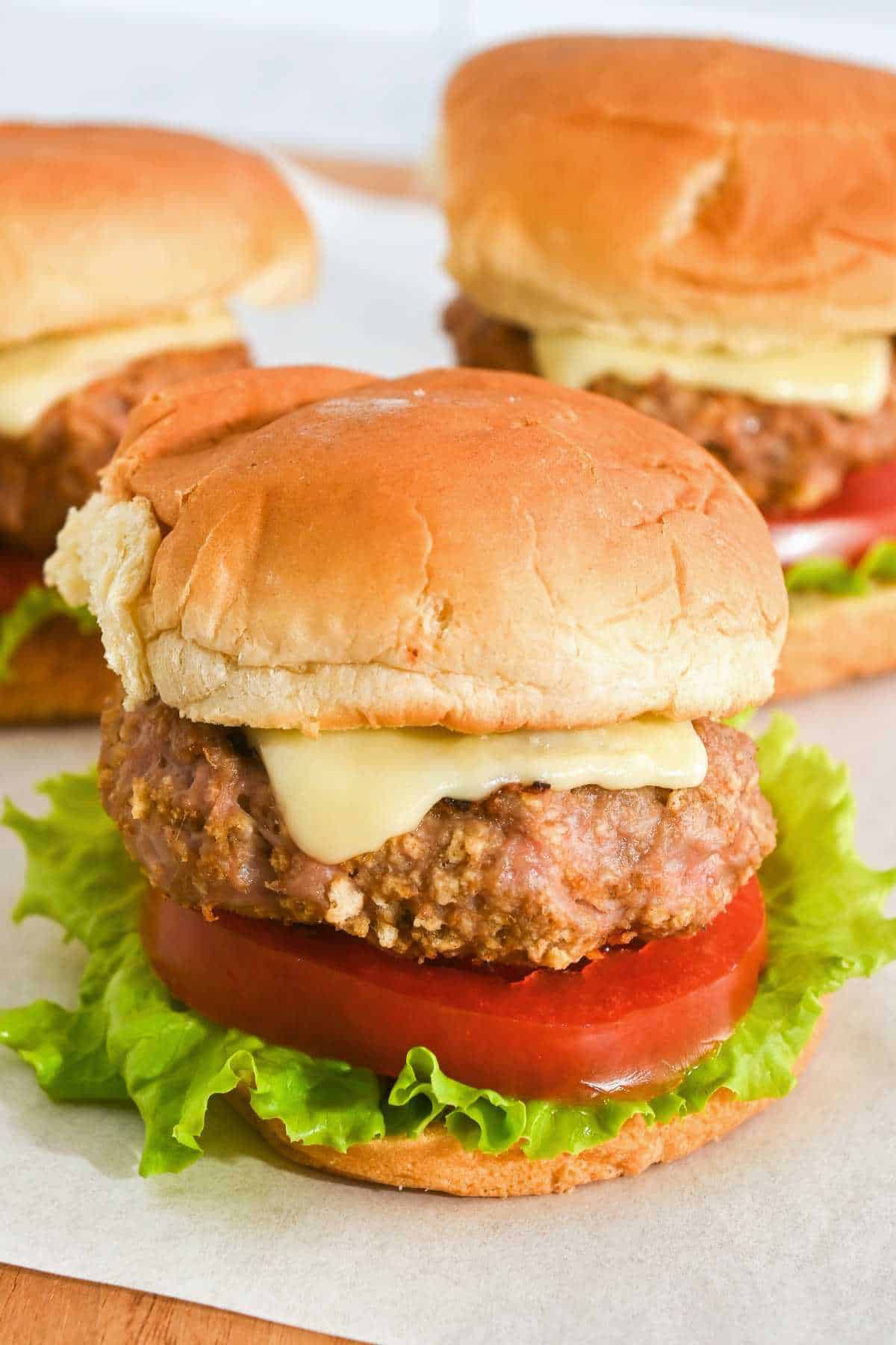 three turkey burger sliders on Hawaiian rolls on parchment paper.l