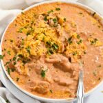 close up of bowl of creamy chicken taco soup in a white bowl with a spoon.