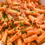 close up shot of lobster bisque pasta topped with fresh basil and parmesan cheese.